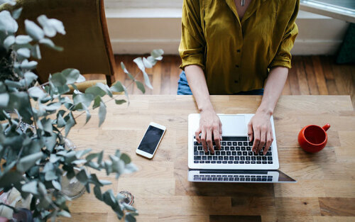 Woman typing blog posts on her laptop