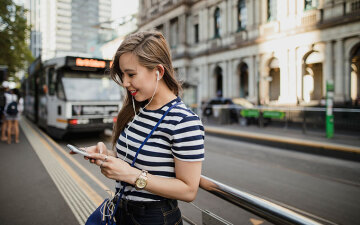 Woman using a smartphone as she waits for a tram in Melbourne CBD