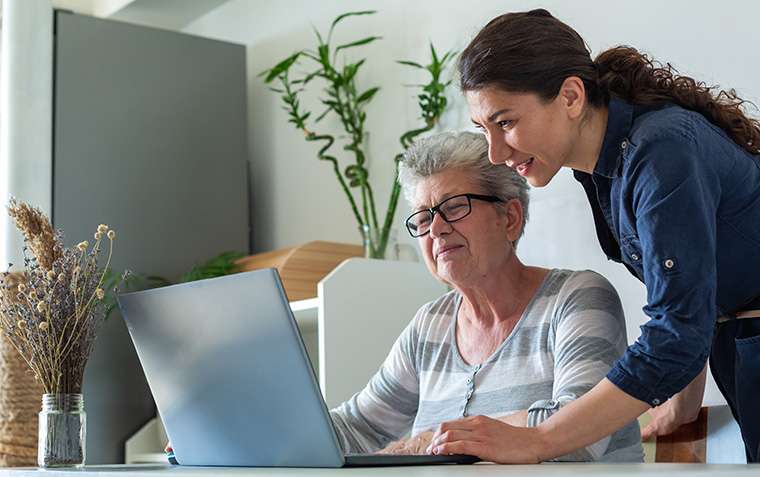 Senior women and young women using laptop at home