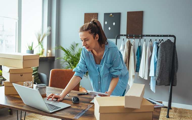 Women, owener of small business packing product in boxes