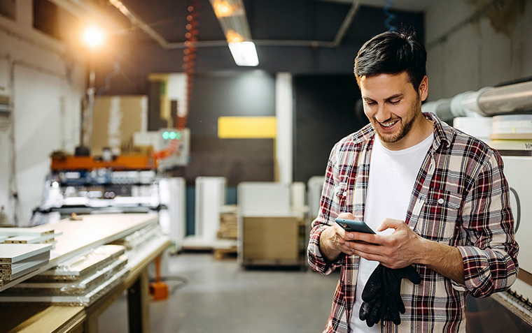 Young smiling casually clothed carpenter using phone