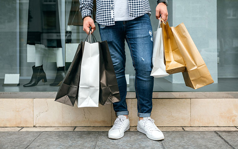 Low section of unrecognisable young man shopping with paper bags in his hand