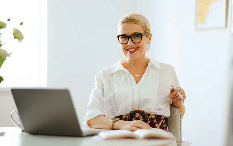 Smiling business woman in her early 40s sitting in front of a laptop