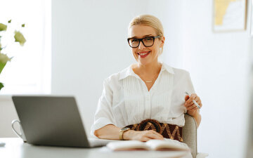 Smiling business woman in her early 40s sitting in front of a laptop