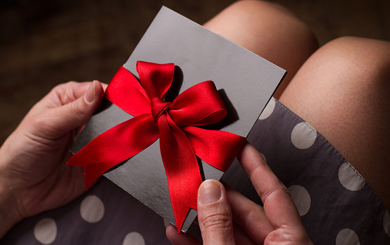 Woman opening a gift voucher in a red bow
