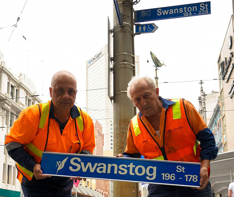 Workers holding a Swanstog Street sign